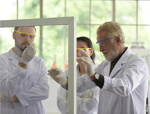 A team of researchers in lab coats and goggles, working together on scientific experiments in a laboratory space.